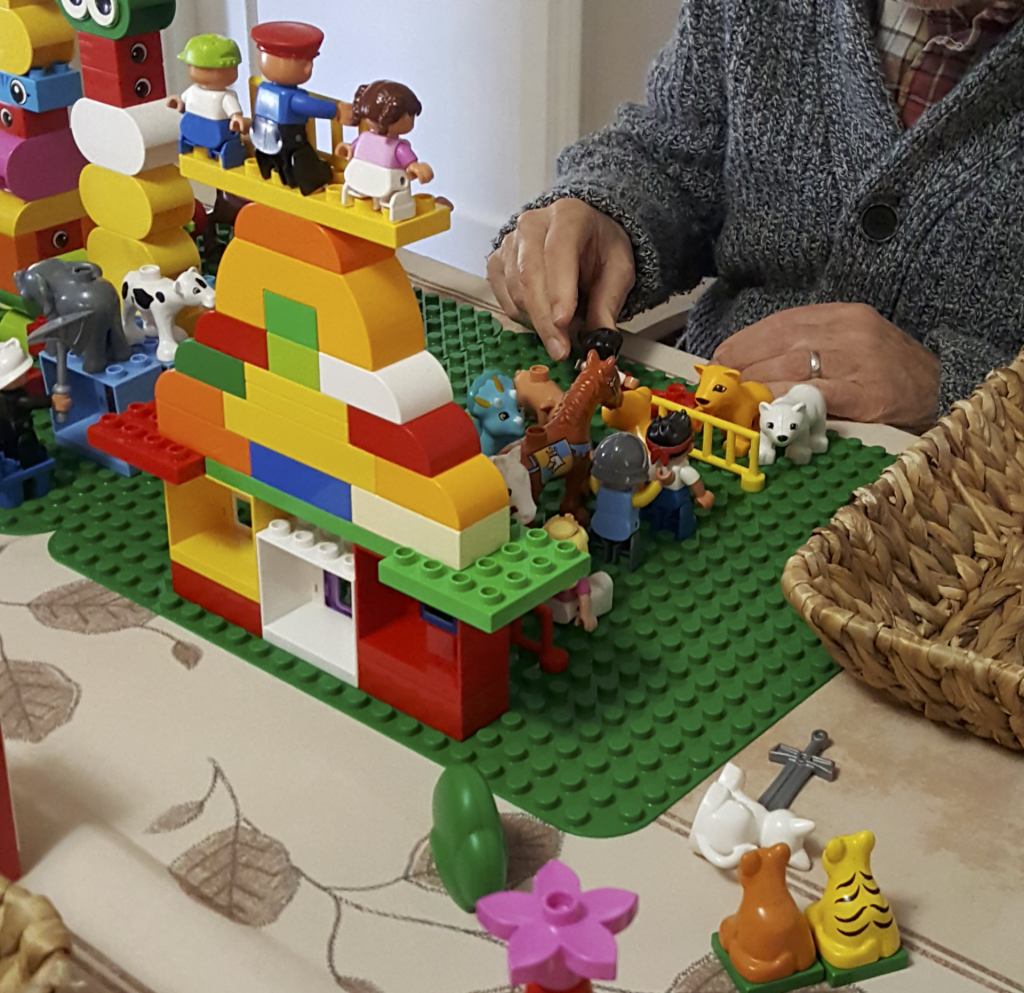 Hands of Older Adult building with LEGO Duplo bricks and pieces